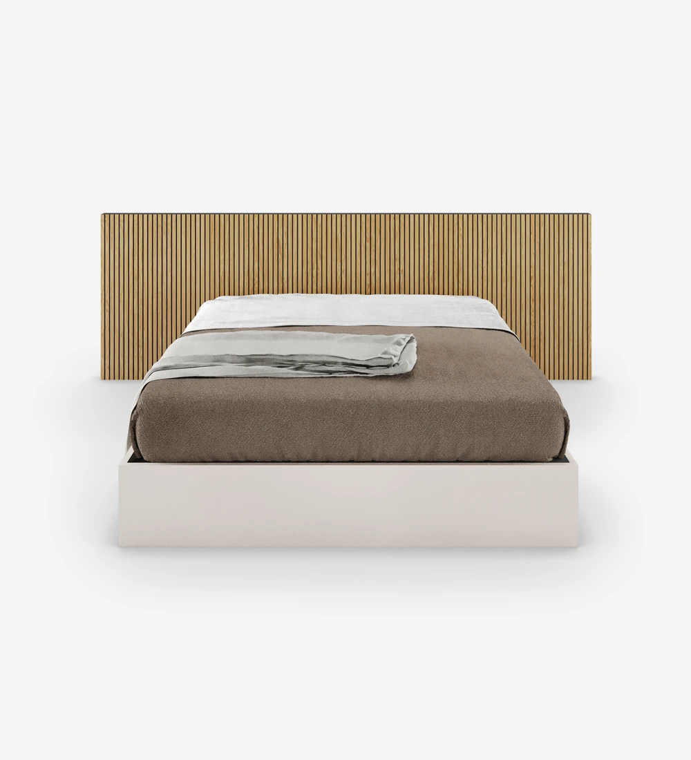 Lit double avec tête de lit avec frises en chêne naturel et sommier perle, avec rangement via un lit surélevé.
