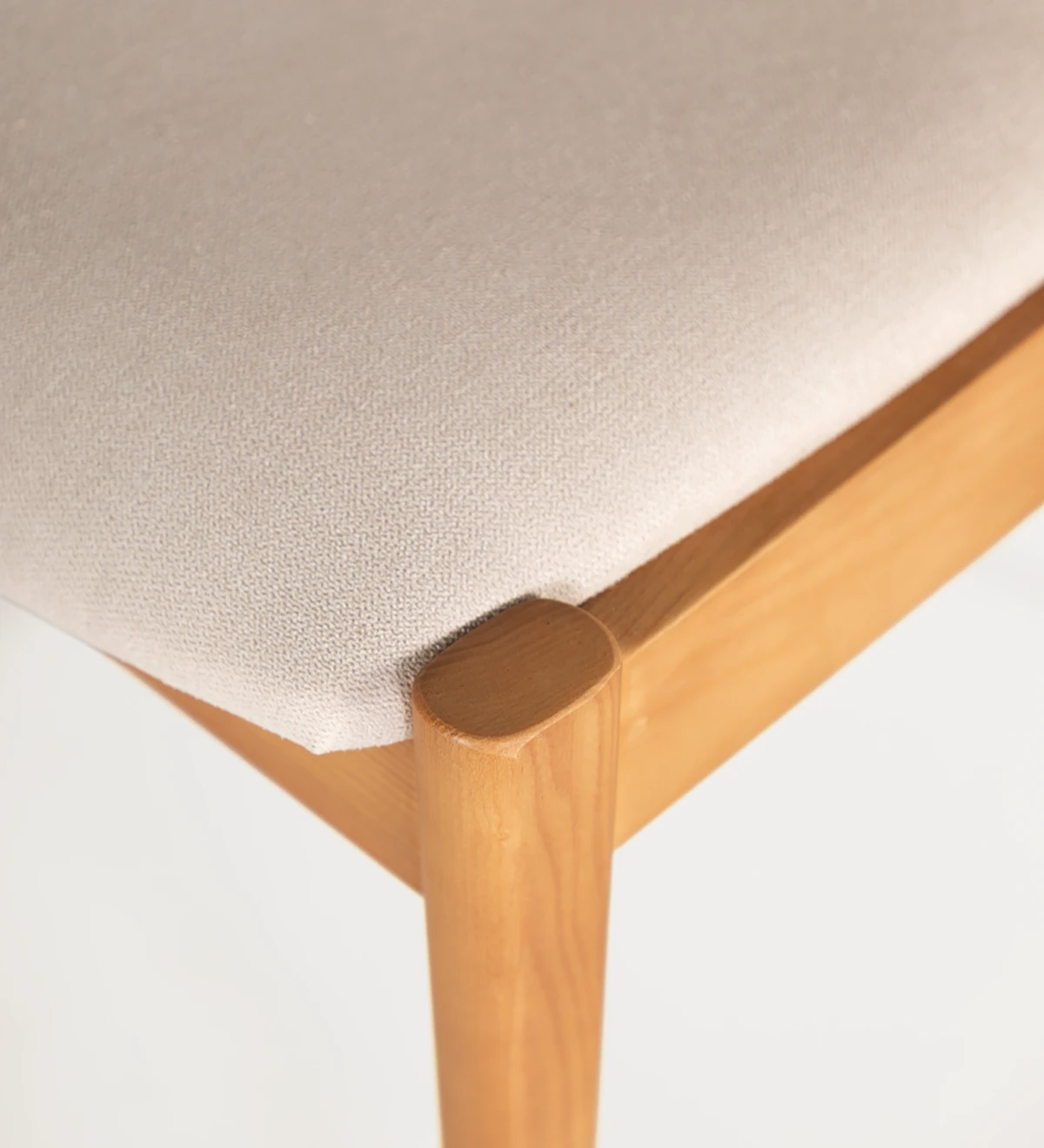 Silla en madera de fresno color miel, con asiento y respaldo tapizado en tejido.