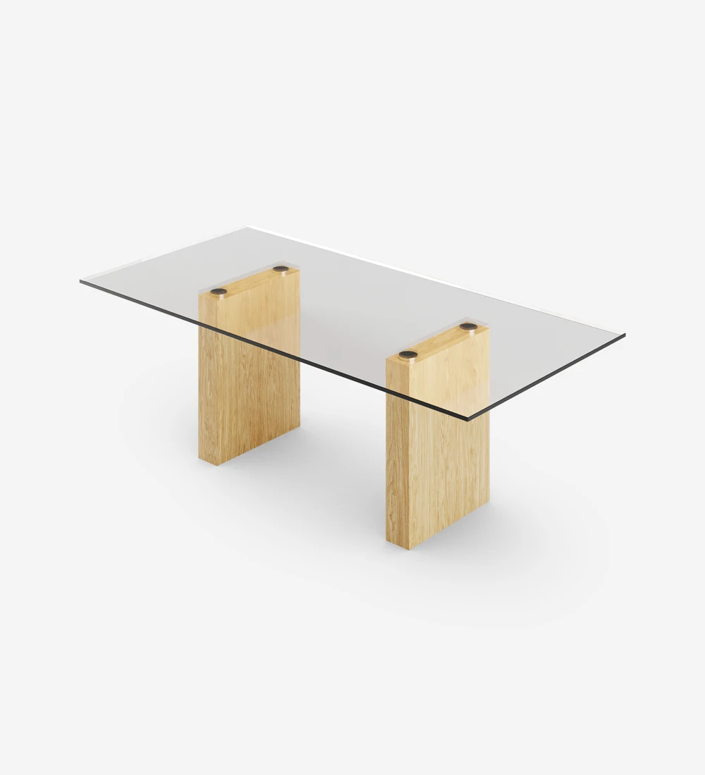Mesa de comedor rectangular con tapa de cristal y pies de roble natural.