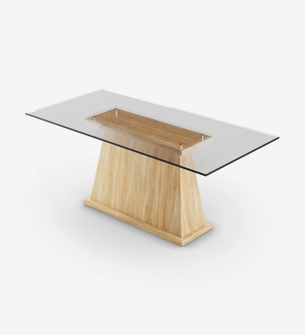 Mesa de comedor rectangular con tapa de cristal y pie central en roble de color natural.