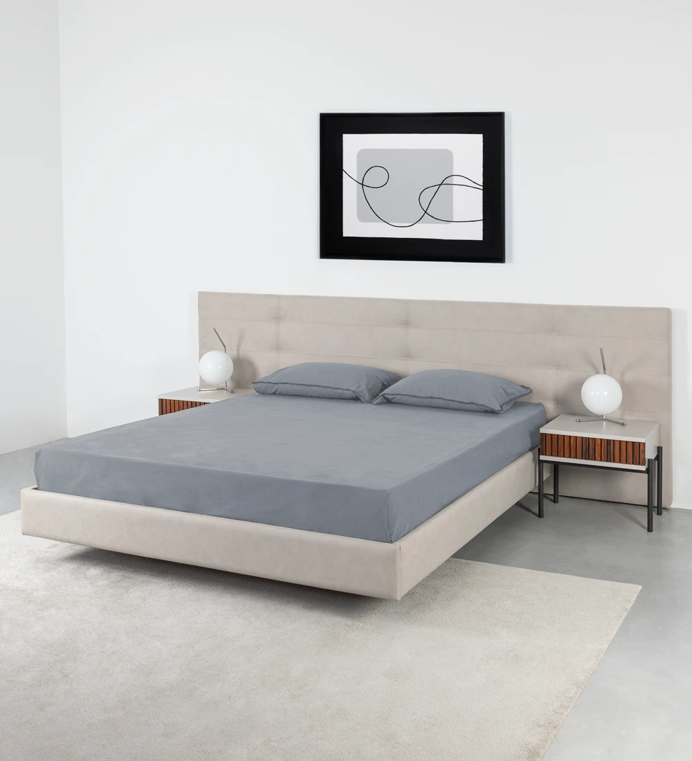 Double bed with headboard with rectangles, upholstered in fabric, with suspended footboard.