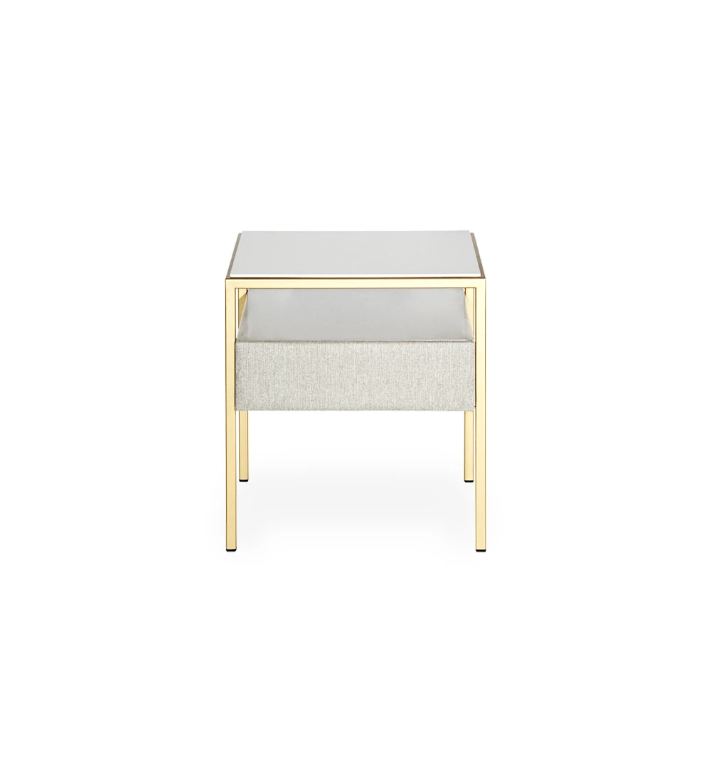 Table de chevet à 1 tiroir avec façade tapissée en tissu, plateau et module de tiroir laqués en perle, pied en métal laqué en or.