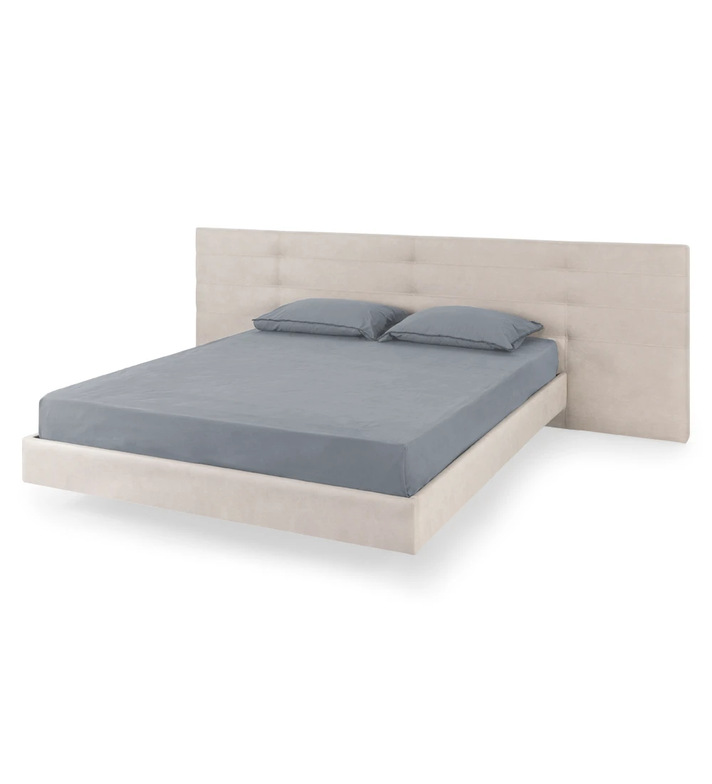 Lit double avec tête de lit à rectangles, recouvert de tissu, avec pied de lit suspendu.