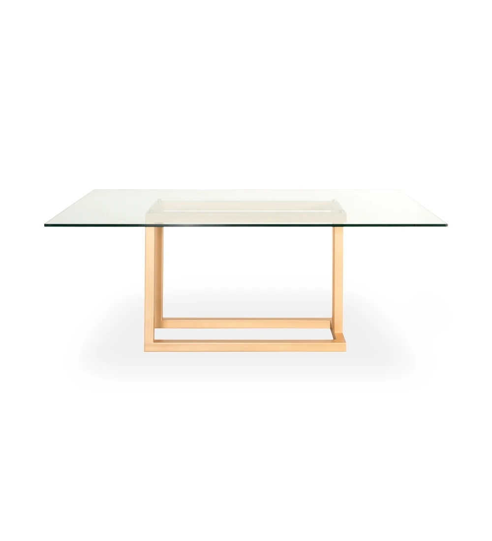 Table de repas rectangulaire avec plateau en verre et pied en métal laqué or.