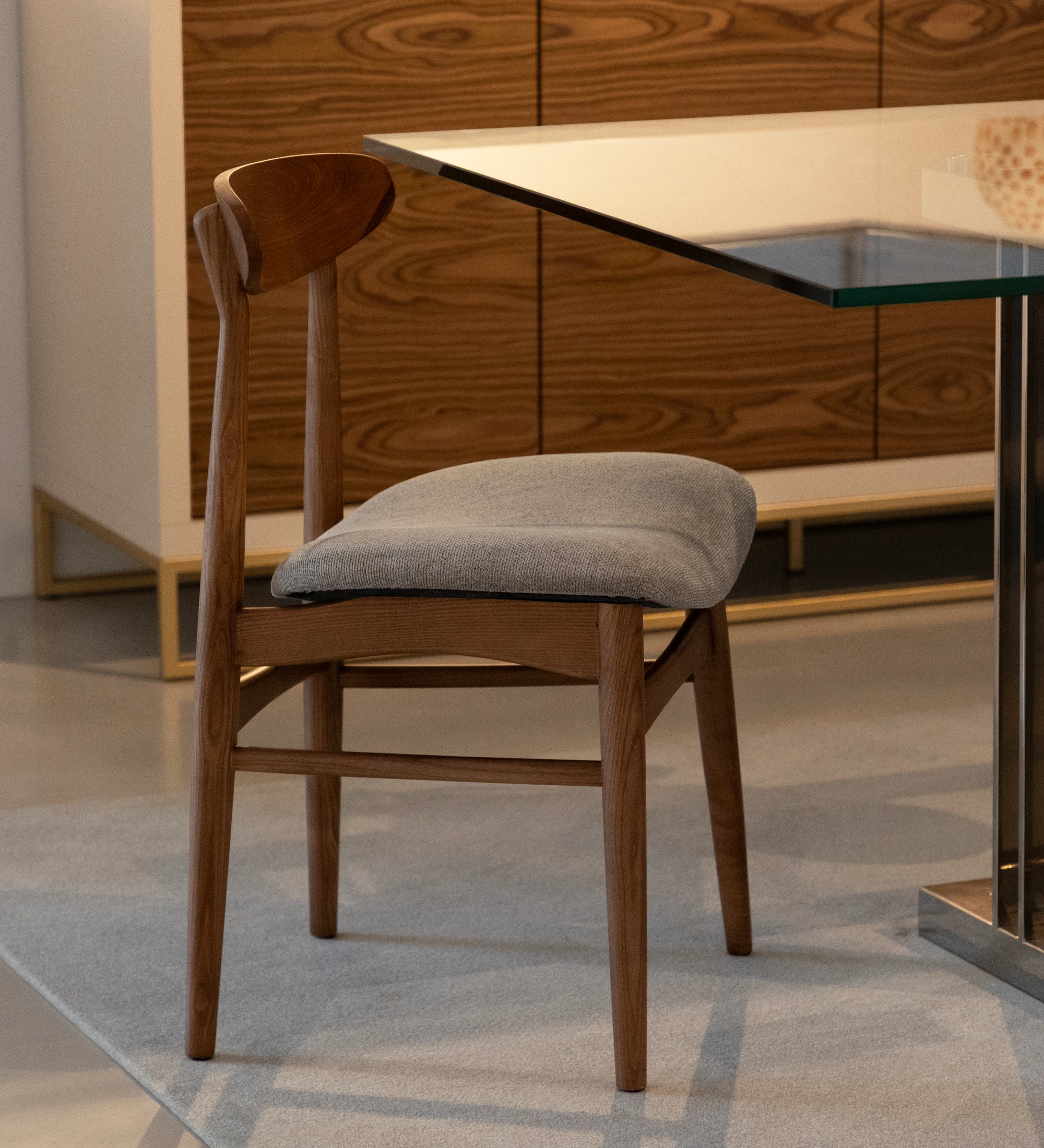 Chair with walnut wood structure and fabric upholstered seat.