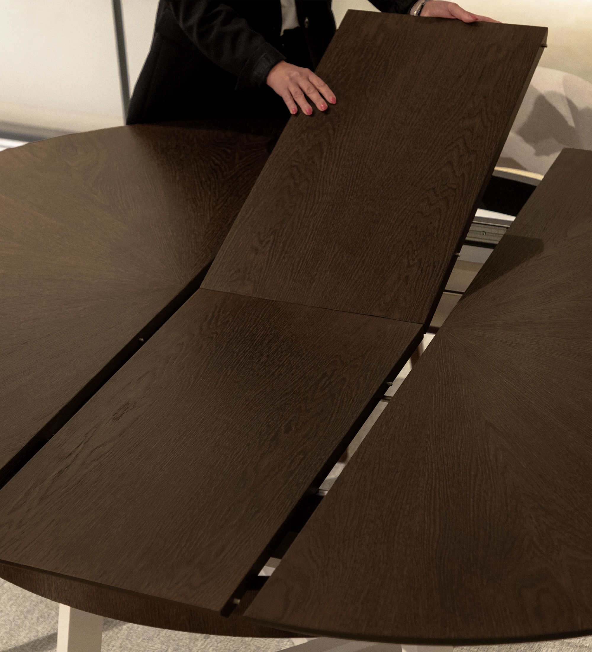 Table de repas ronde extensible avec plateau en chêne noyer et pieds laqués perle.
