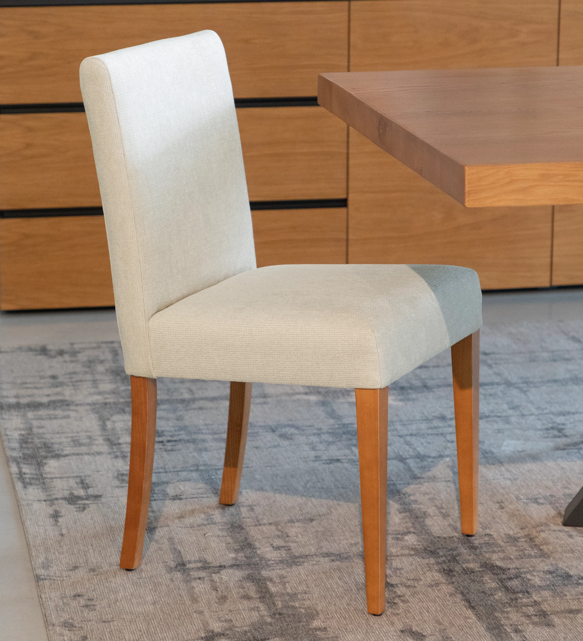 Chaise tapissée de tissu beige, avec pieds en bois couleur miel.