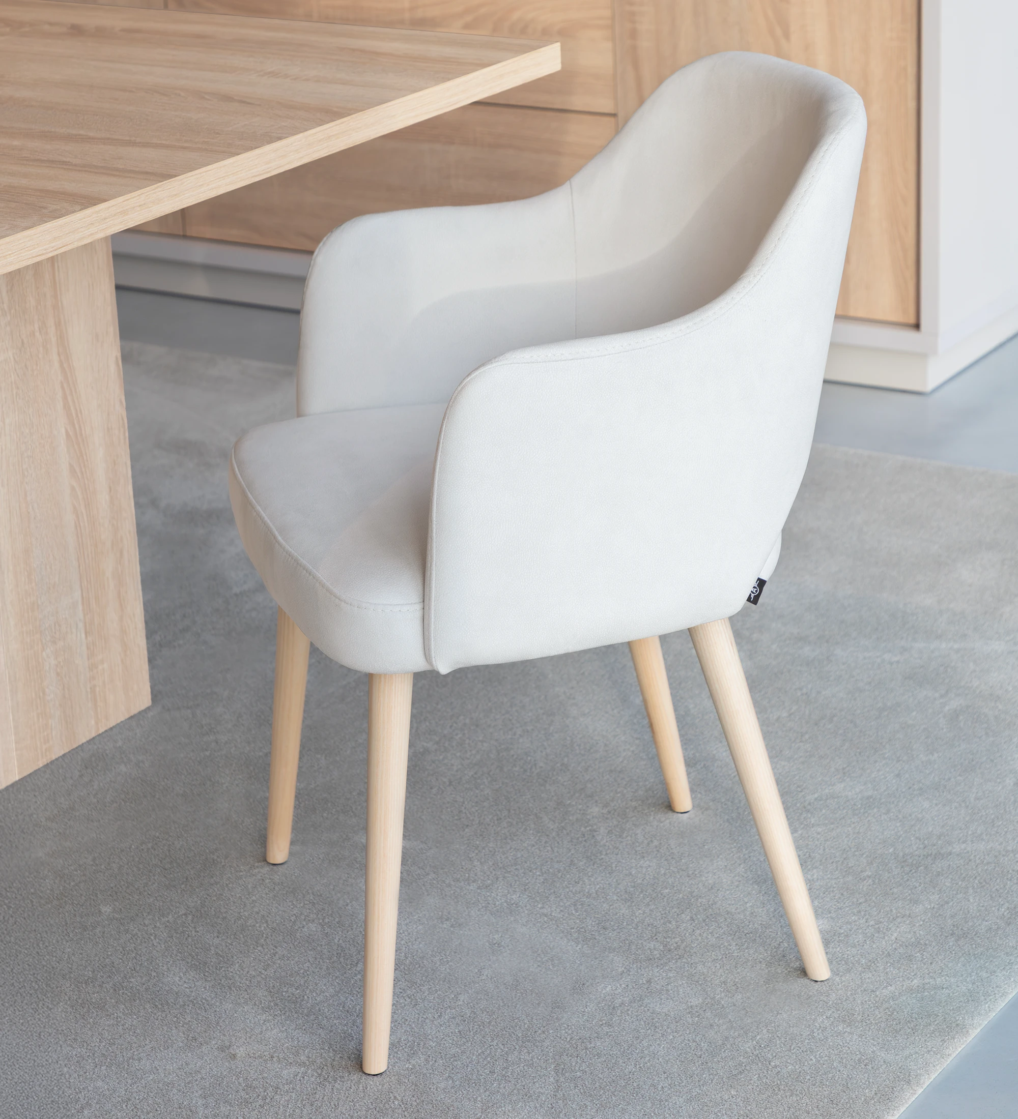 Chair with arms upholstered in pearl fabric, with natural colored wooden legs.