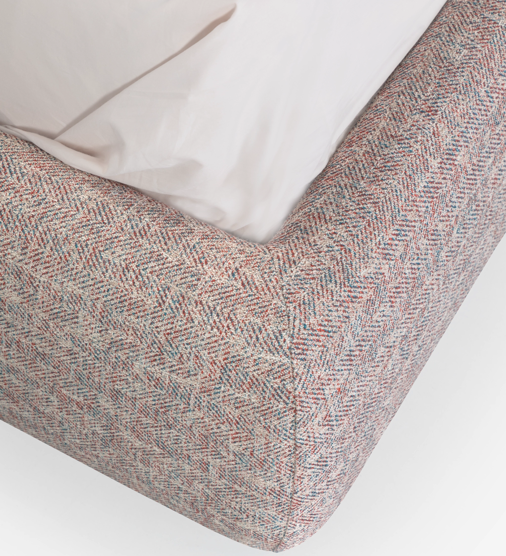 Double bed with short headboard, upholstered in multicolored fabric, primarily red and blue.
