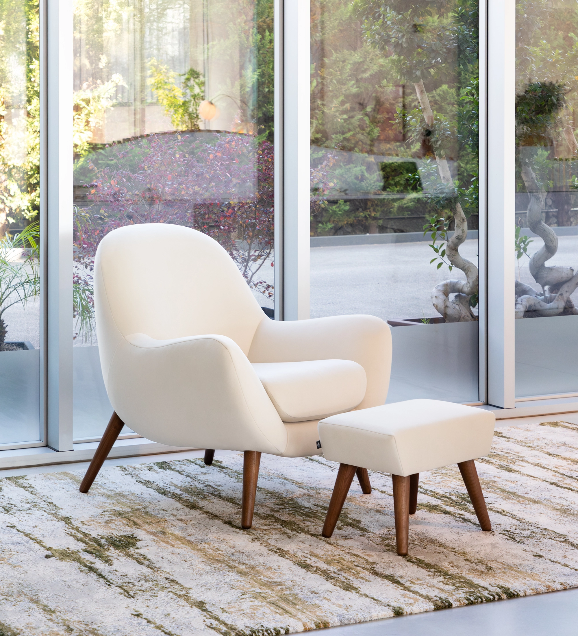 Fauteuil Oslo revêtu de tissu couleur perle avec pieds en frêne teinté noyer.