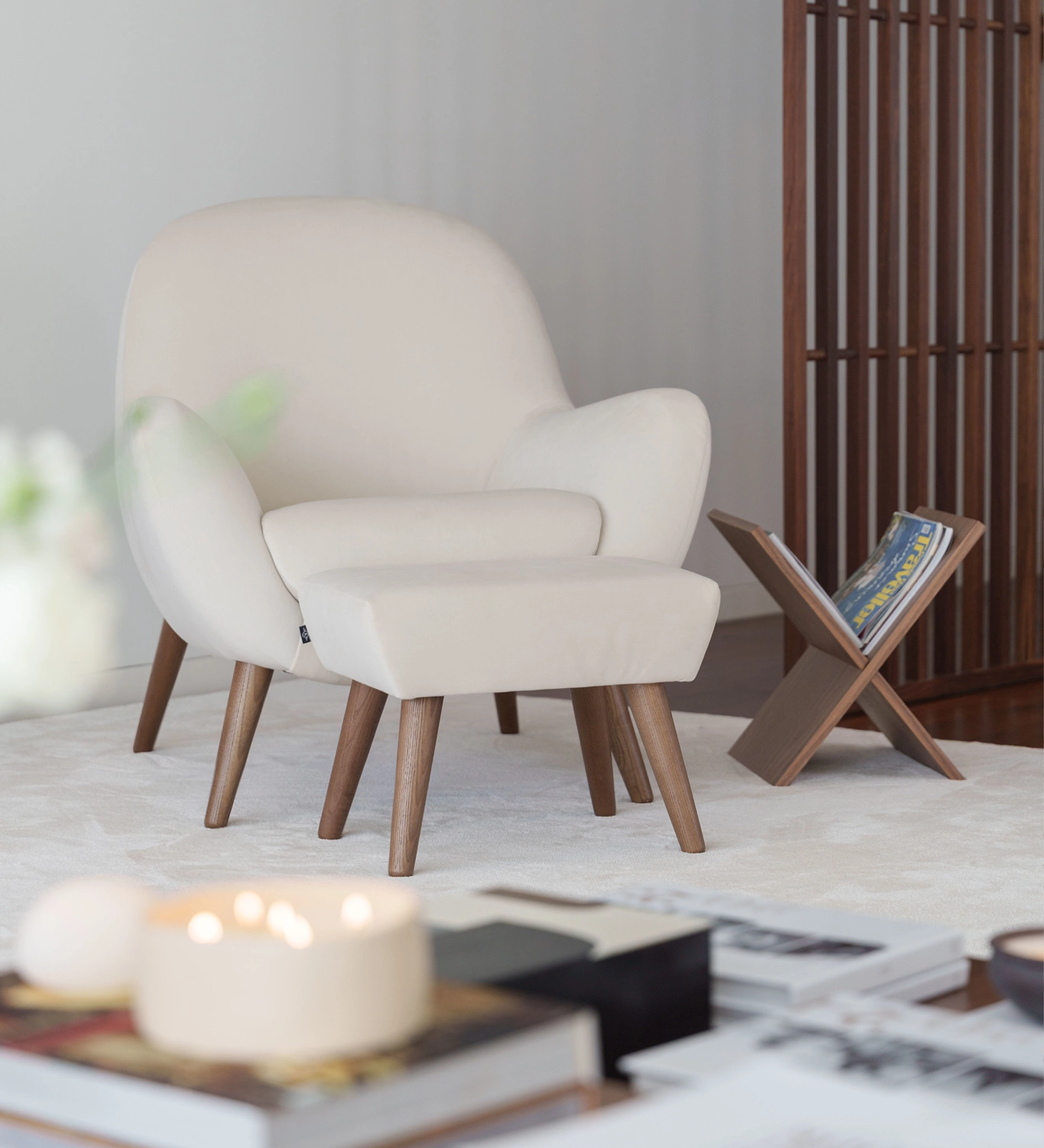Sillón Oslo blanco con reposapiés y patas de madera junto a ventanal