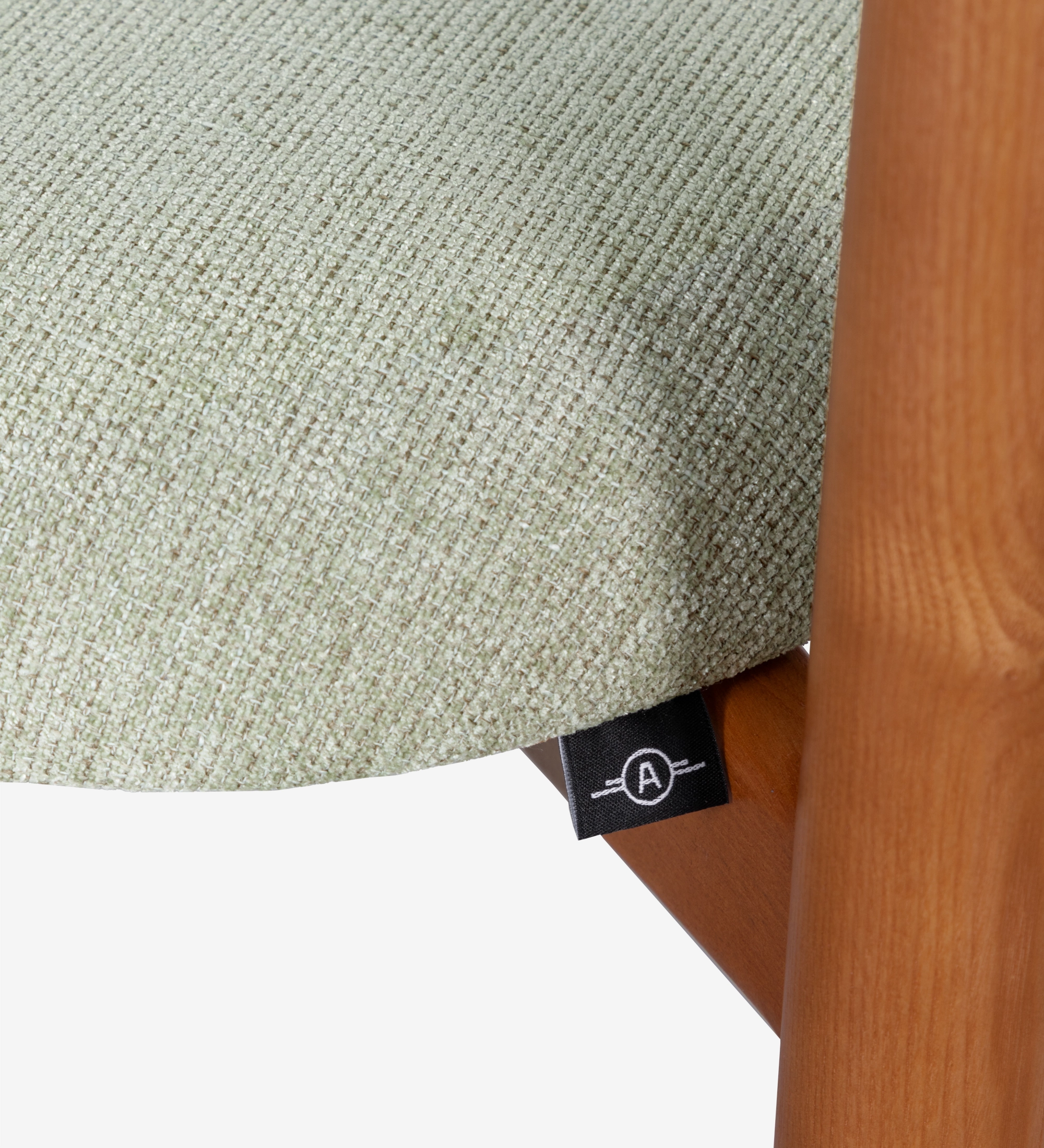 Silla de madera de fresno color miel, con asiento y respaldo tapizados en tela verde.