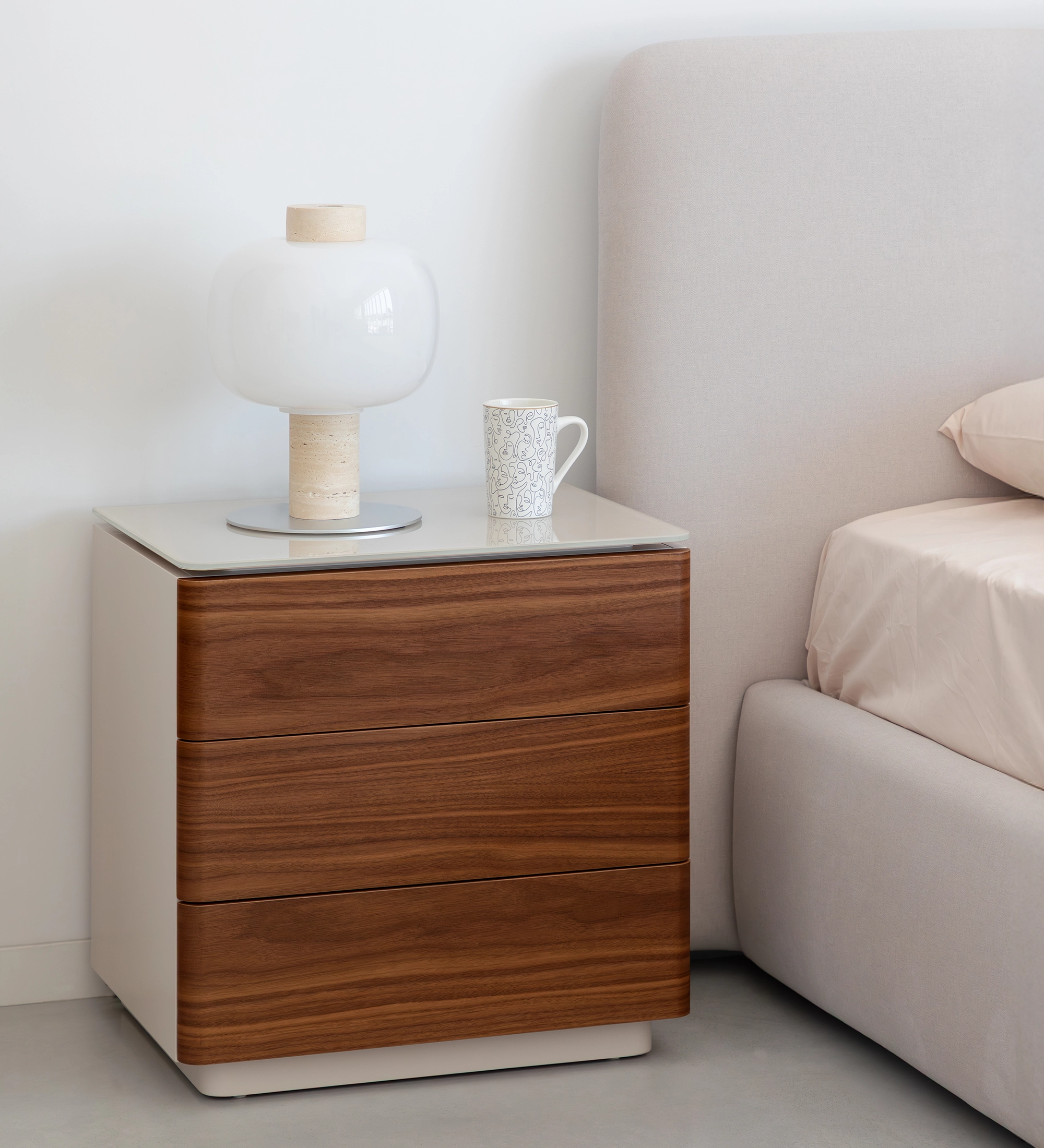 Bedside table with 3 drawers in natural walnut, pearl-lacquered structure and glass top. 
