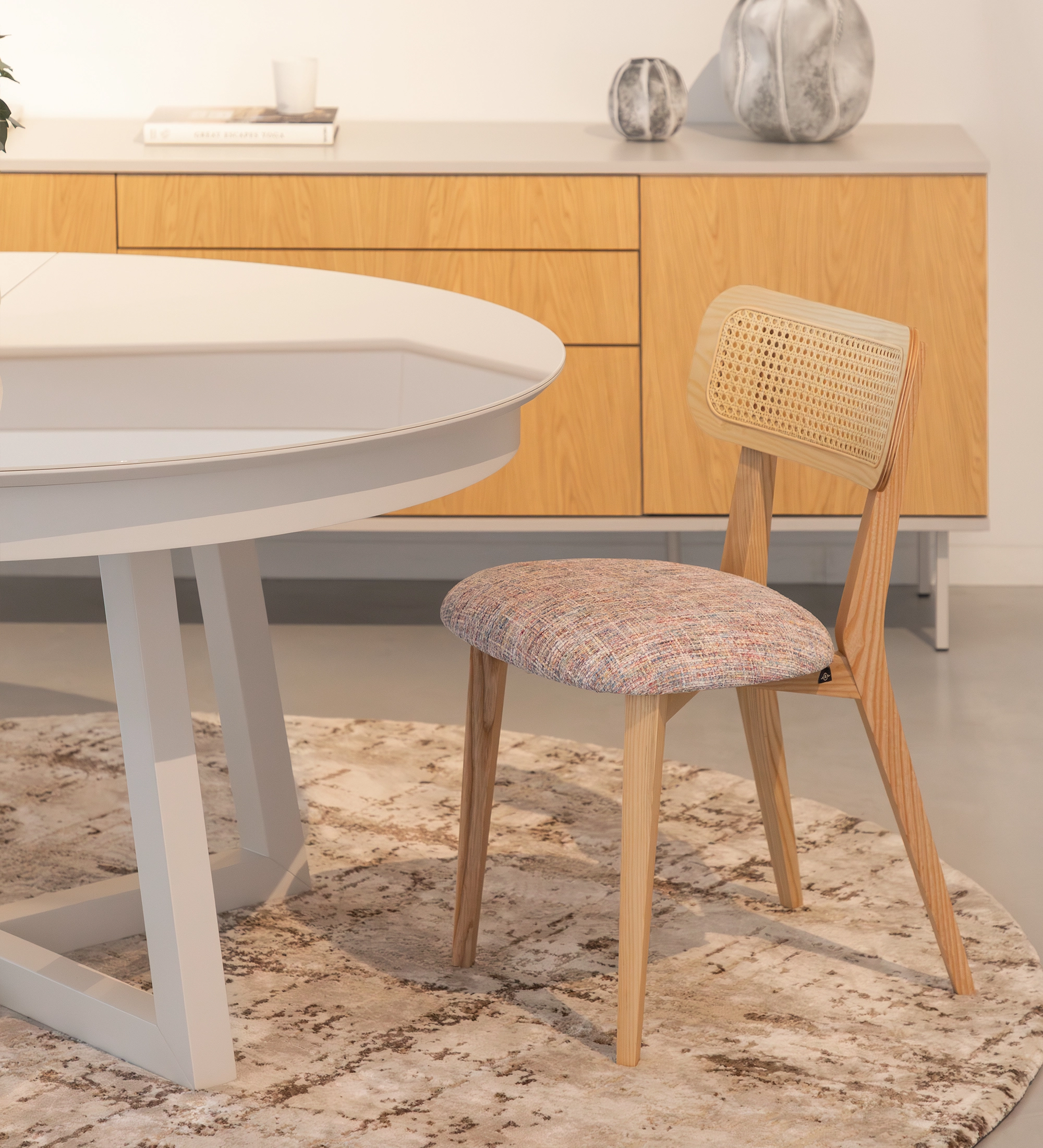 Cadeira de madeira, com pormenor de rattan nas costas e assento estofado a tecido multicolor, primariamente magenta.