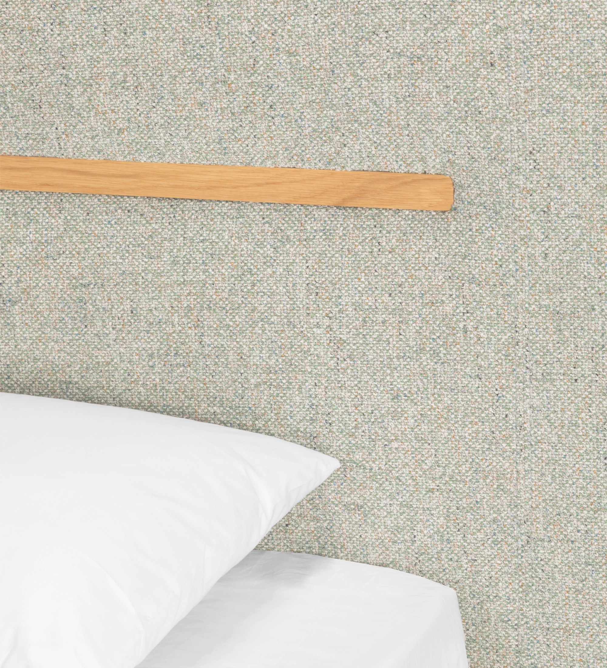 Double bed with upholstered headboard and floating base in green fabric, detail in natural oak.