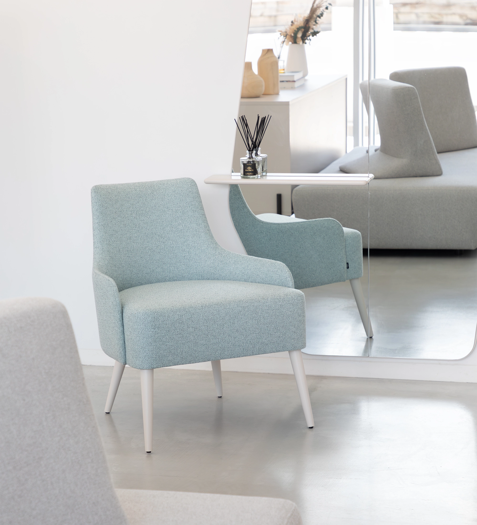 Oslo armchair upholstered in blue fabric, pearl lacquered feet.