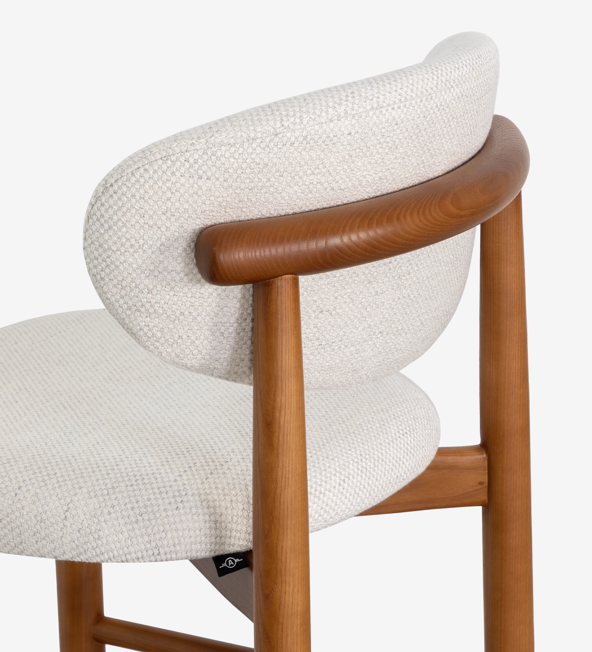 Taburete en madera de fresno color miel, con asiento y respaldo tapizados en tela beige.