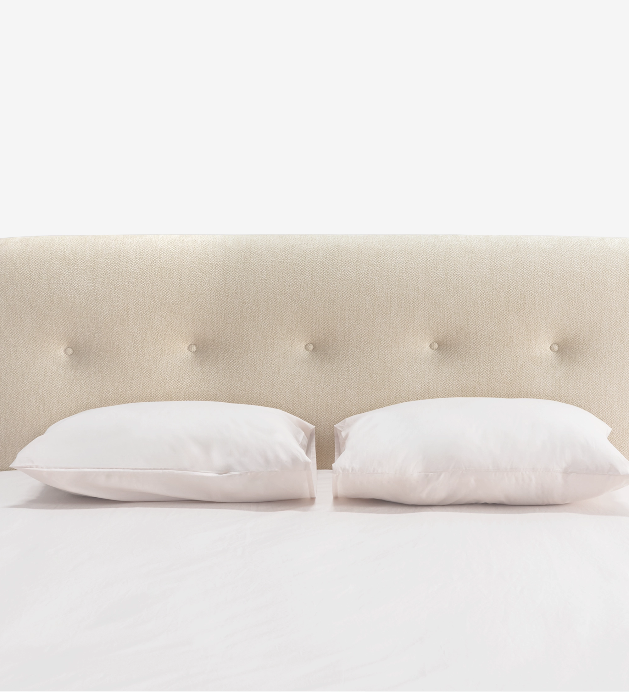 Cama doble con cabecero corto, tapizada en tela beige.