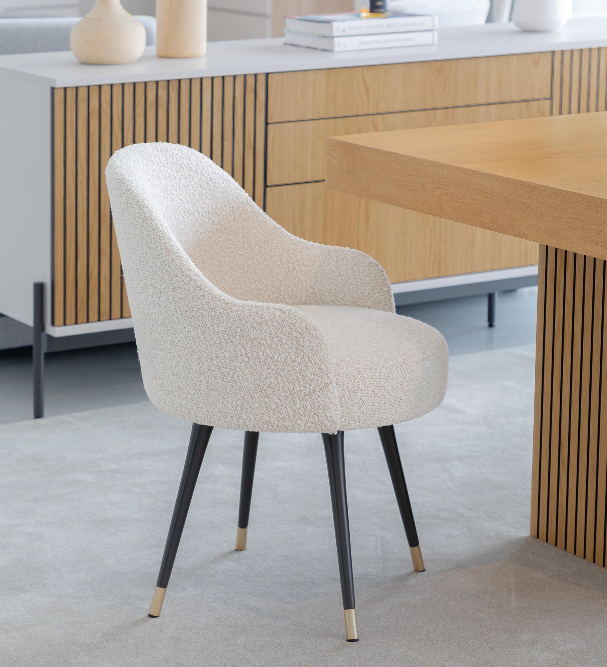 Silla giratoria tapizada en tejido perla con pies lacados en negro y detalles dorados.