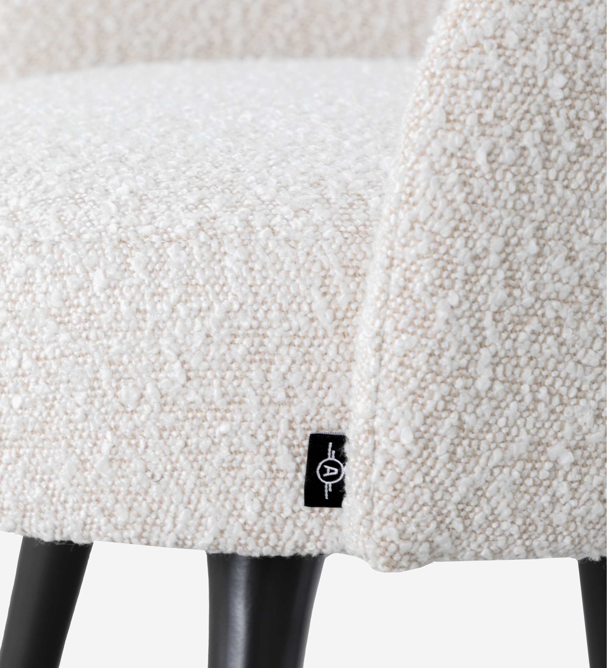 Silla giratoria tapizada en tejido perla con pies lacados en negro y detalles dorados.