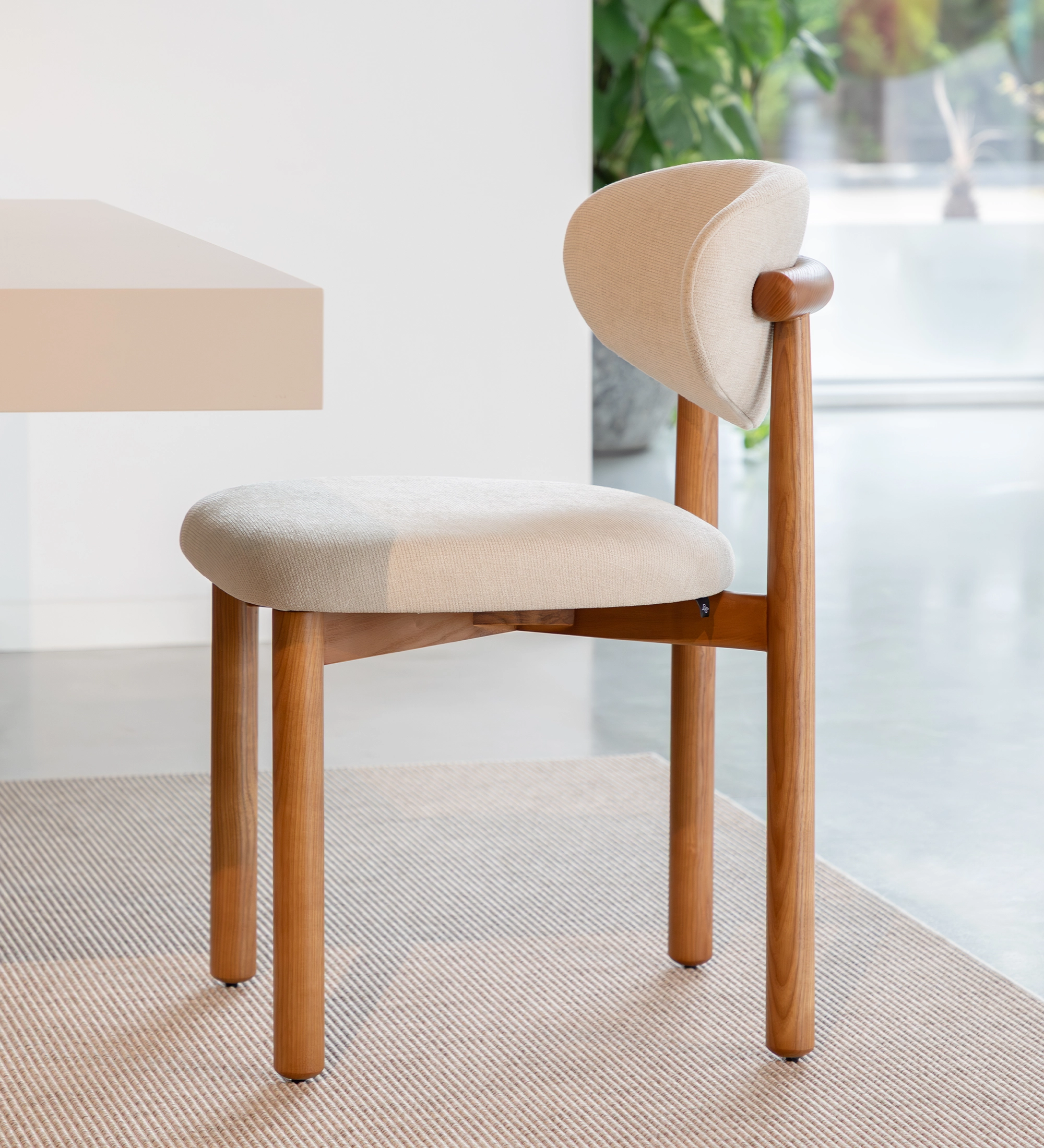 Chaise en bois de frêne couleur miel, avec assise et dossier rembourrés en tissu perle.