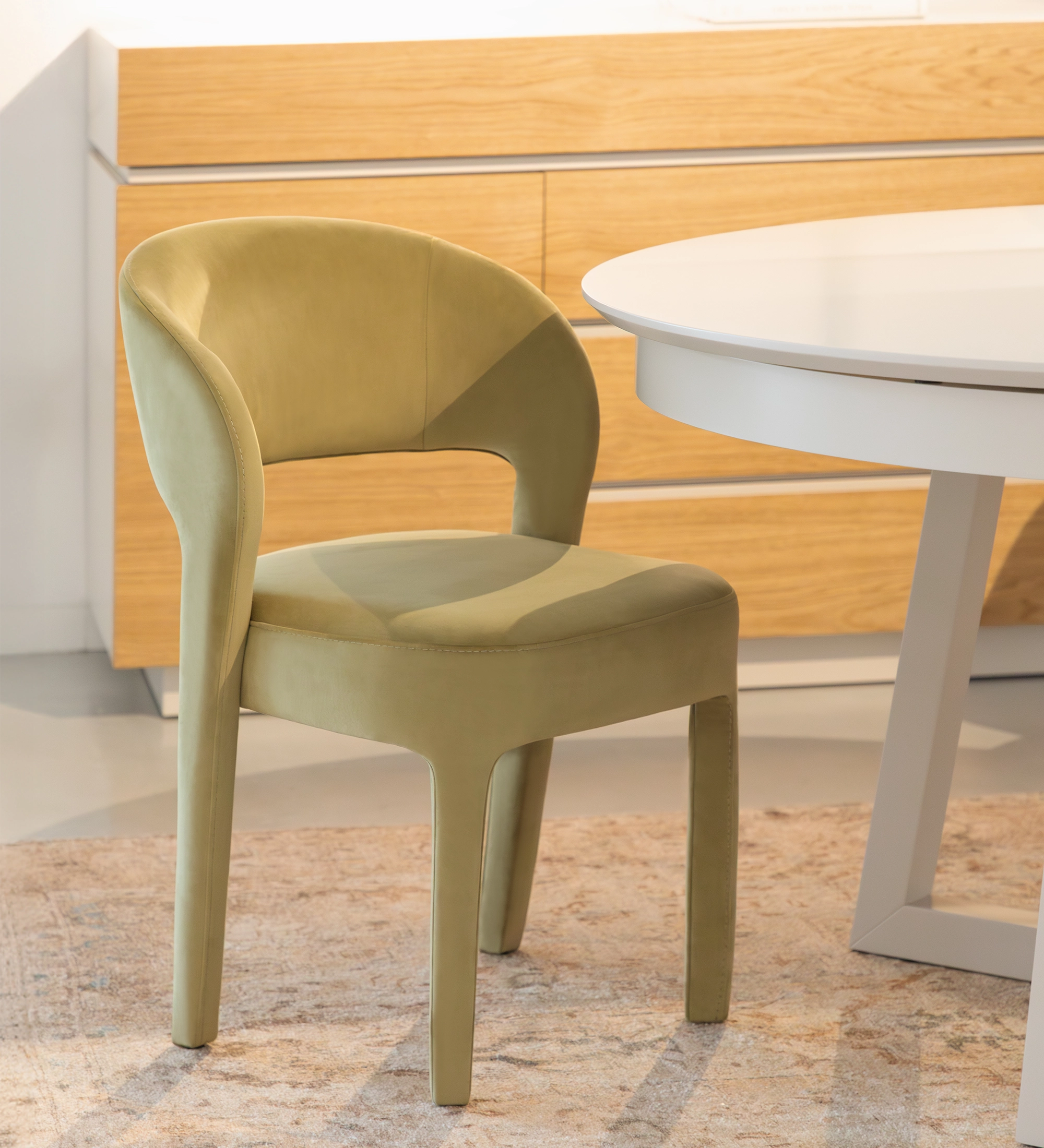 Chaise Mónaco vert olive en velours, dossier arrondi, près d'une table ronde blanche