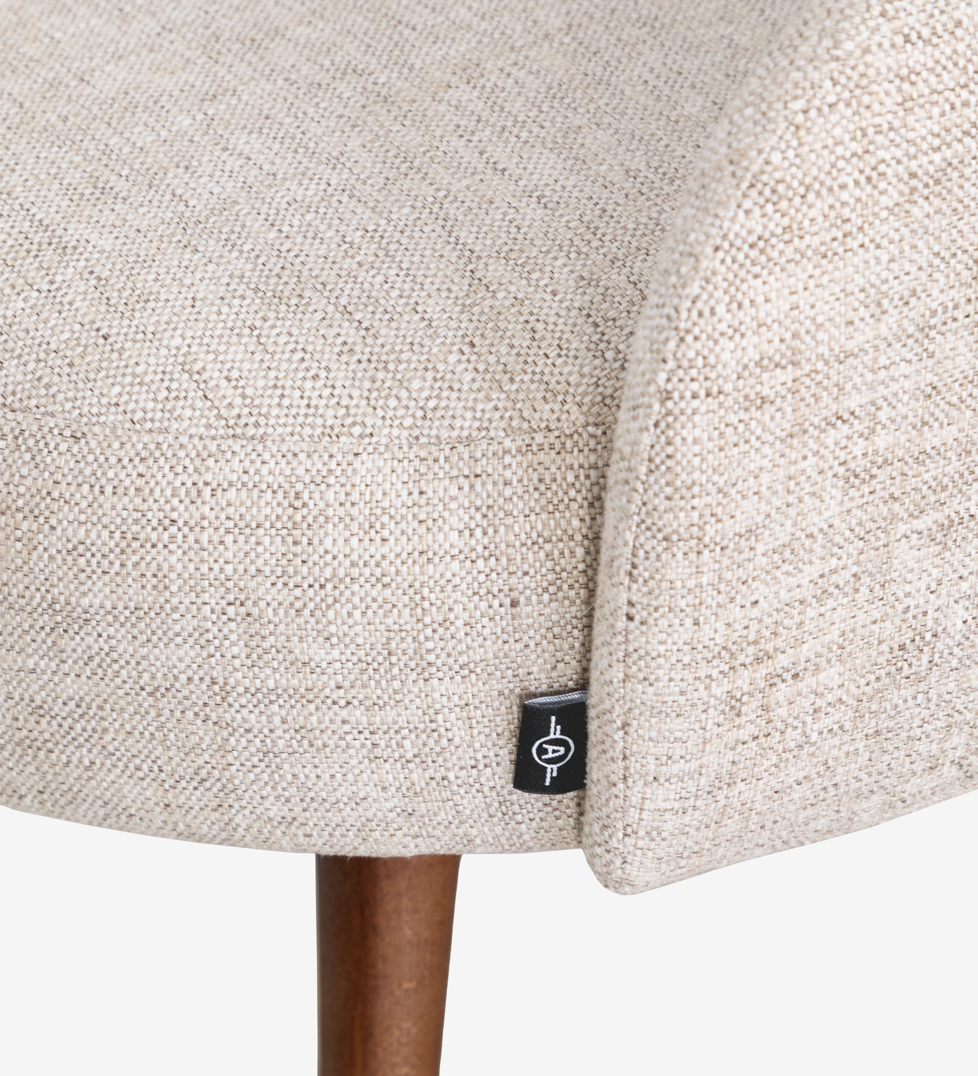 Geneve Chair close-up of beige woven upholstery with black tag and wooden leg