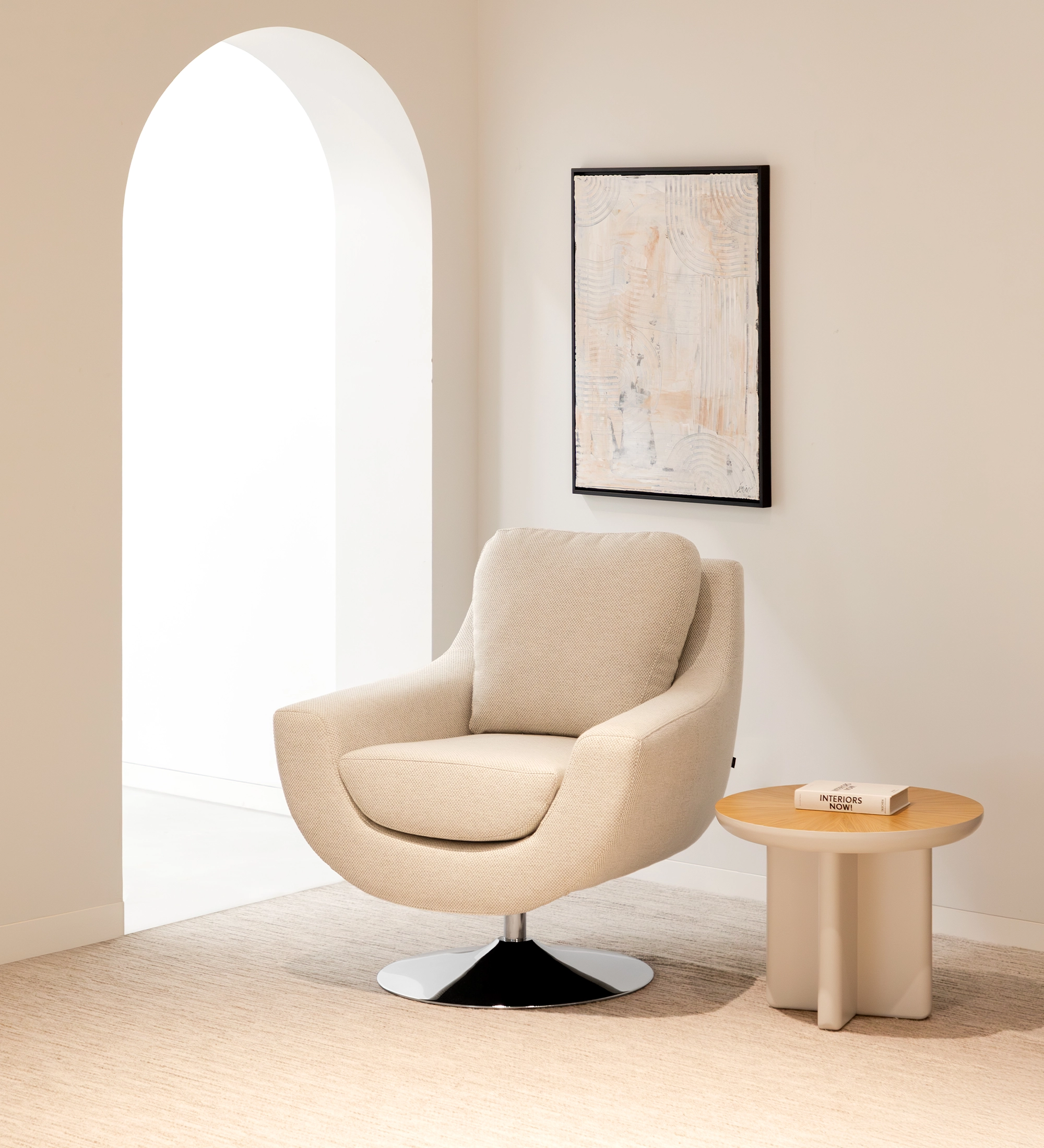 Sillón Paris beige con base giratoria cromada junto a mesa auxiliar y cuadro