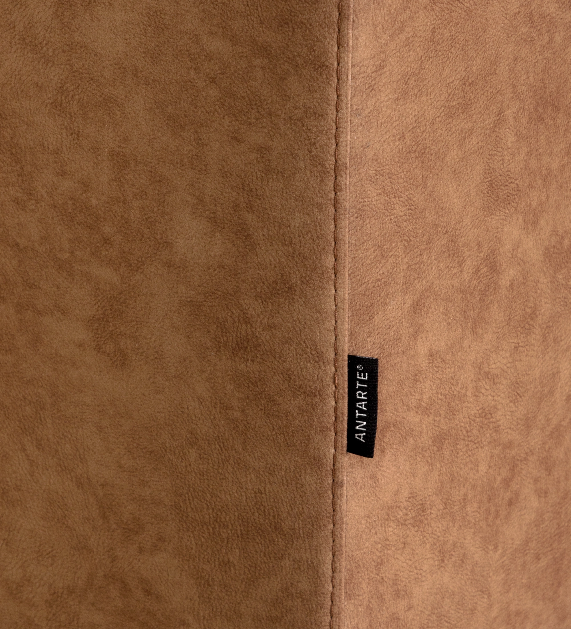 Close-up of tan suede-like upholstery seam and black fabric tag on Barcelona Sofa