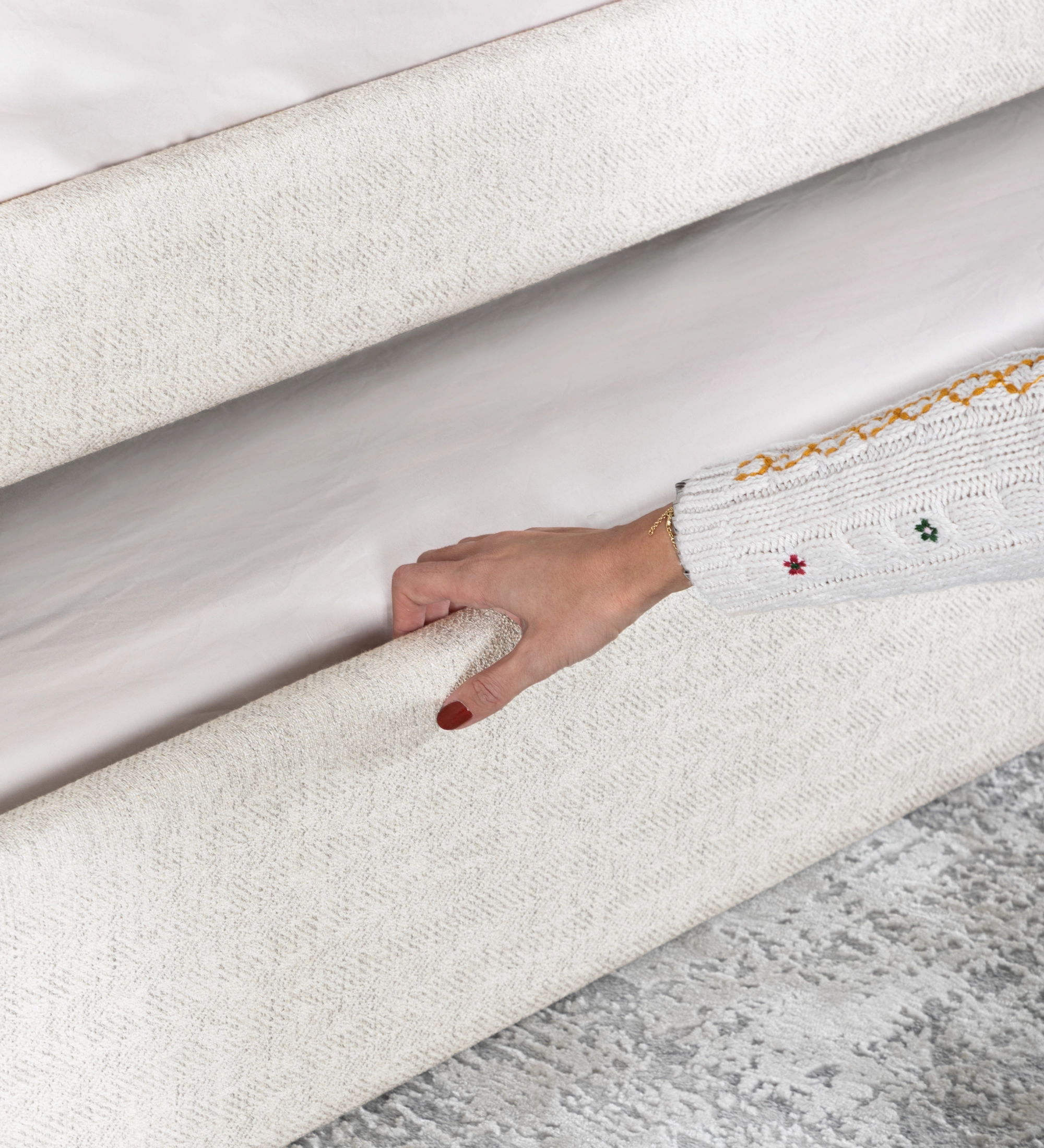 Lit de Divan avec structure et façade de tiroir rembourrées en tissu perle, avec lit dans le tiroir inférieur.