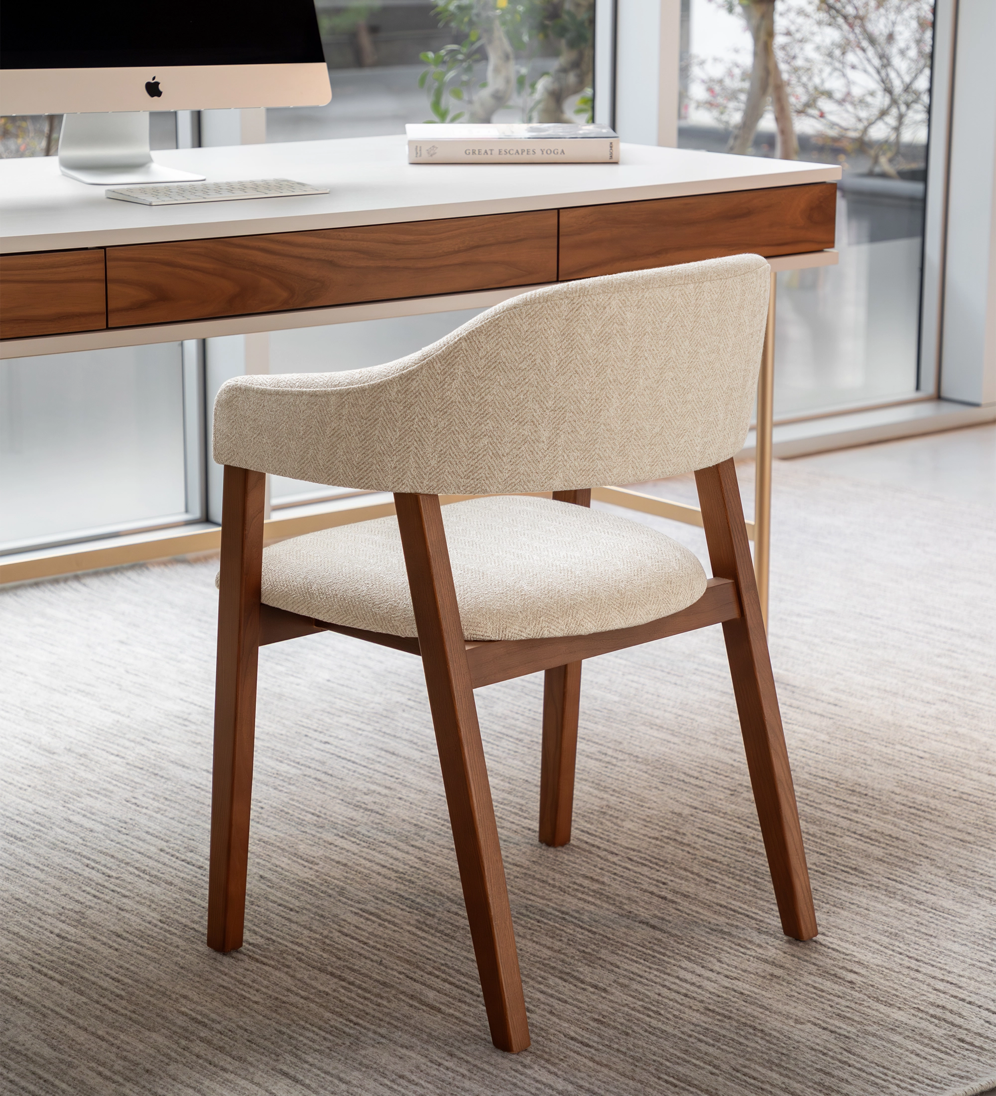 Chair with arms, in walnut-colored ash wood, with seat and back upholstered in beige fabric.