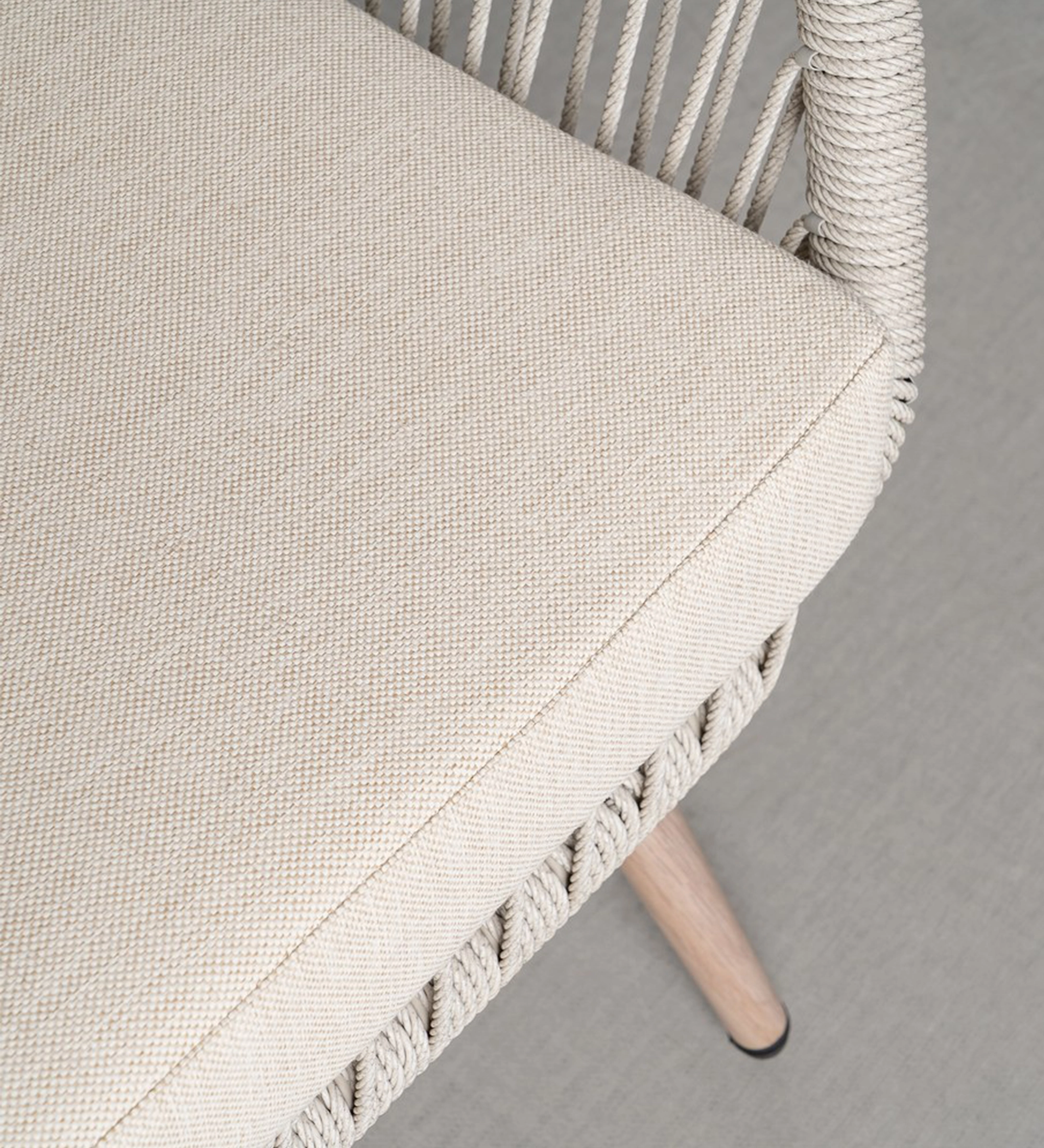 Assento do Conjunto Exterior Caminha com corda entrelaçada, almofada bege e perna de madeira.