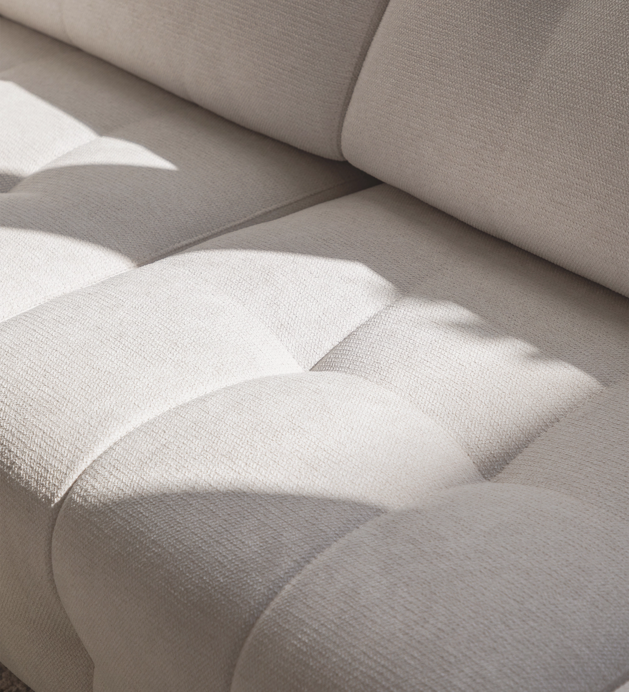 Canapé Madrid beige en tissu texturé, gros plan sur l'assise capitonnée et ombres