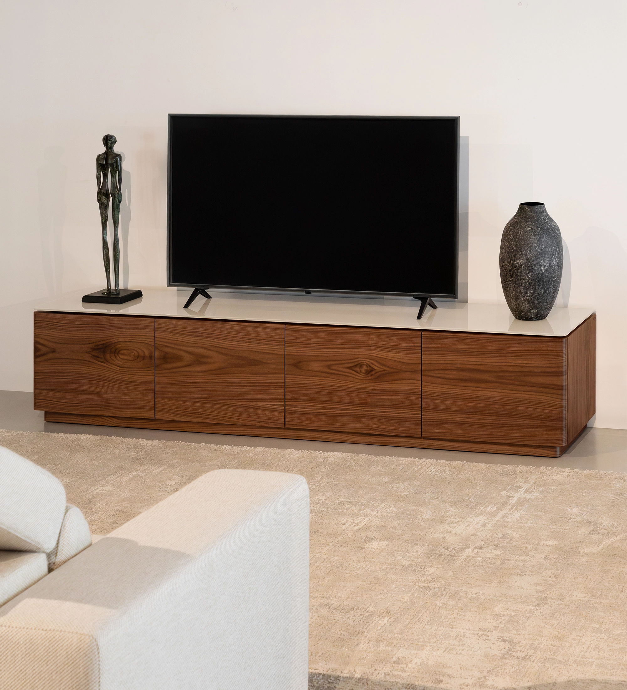 Móvel TV Geneve em madeira com televisão e esculturas decorativas