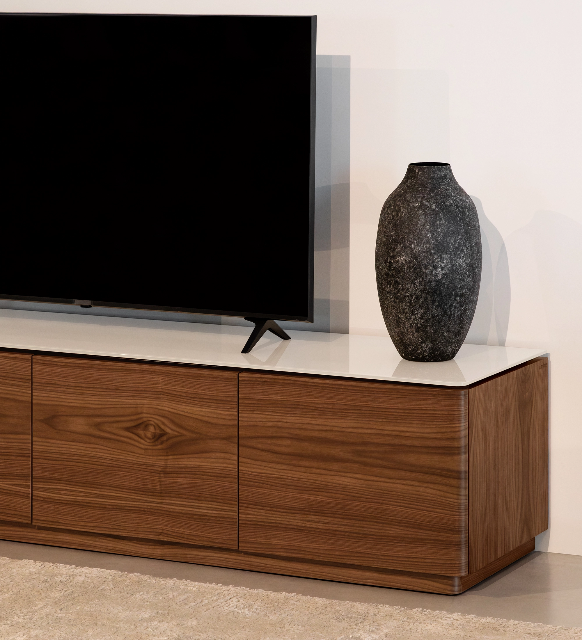 Móvel TV Geneve em madeira com tampo branco, televisão e vaso decorativo