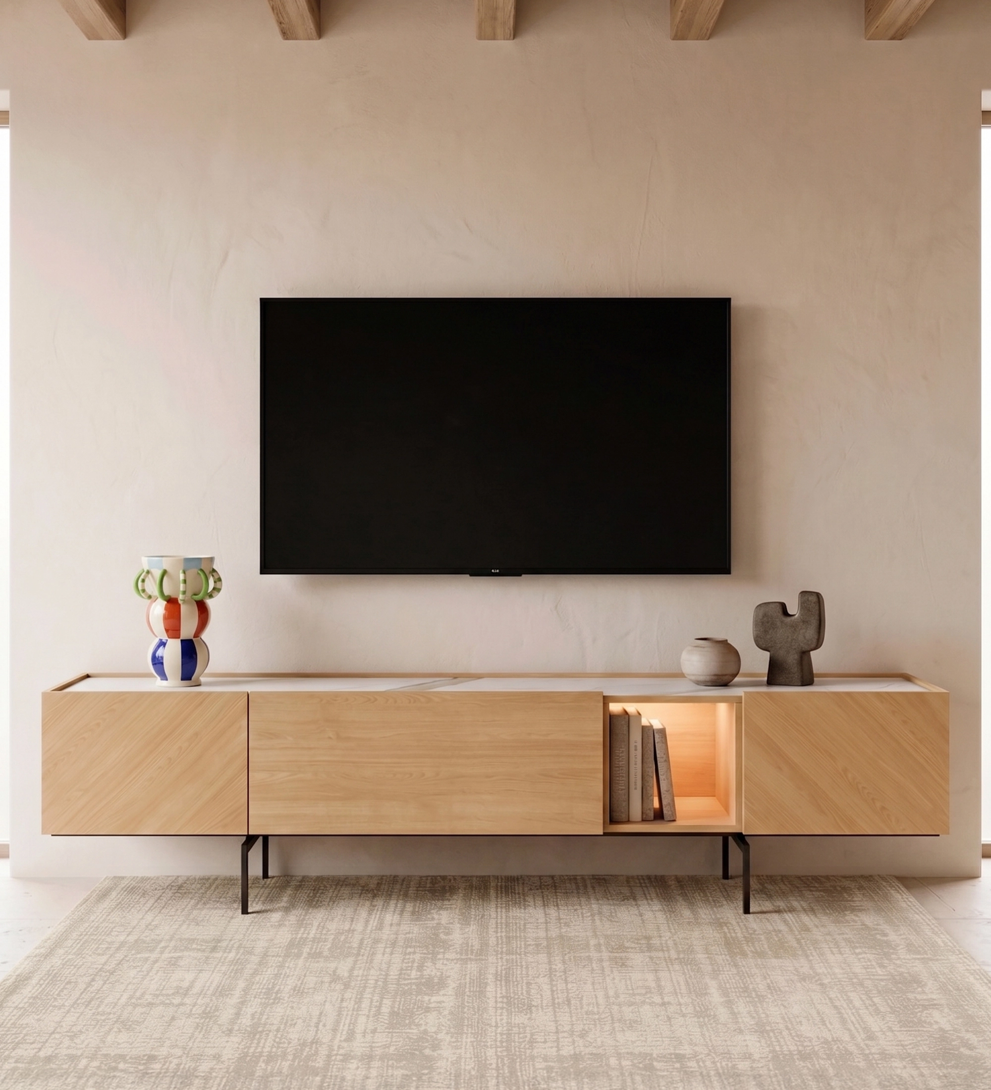 Meuble TV Lagos en bois clair, pieds métalliques, niche éclairée avec livres et objets.