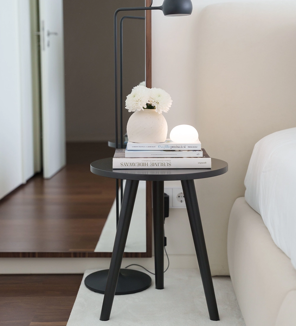 Oslo Side Table with vase of baby's breath and stacked books beside bed