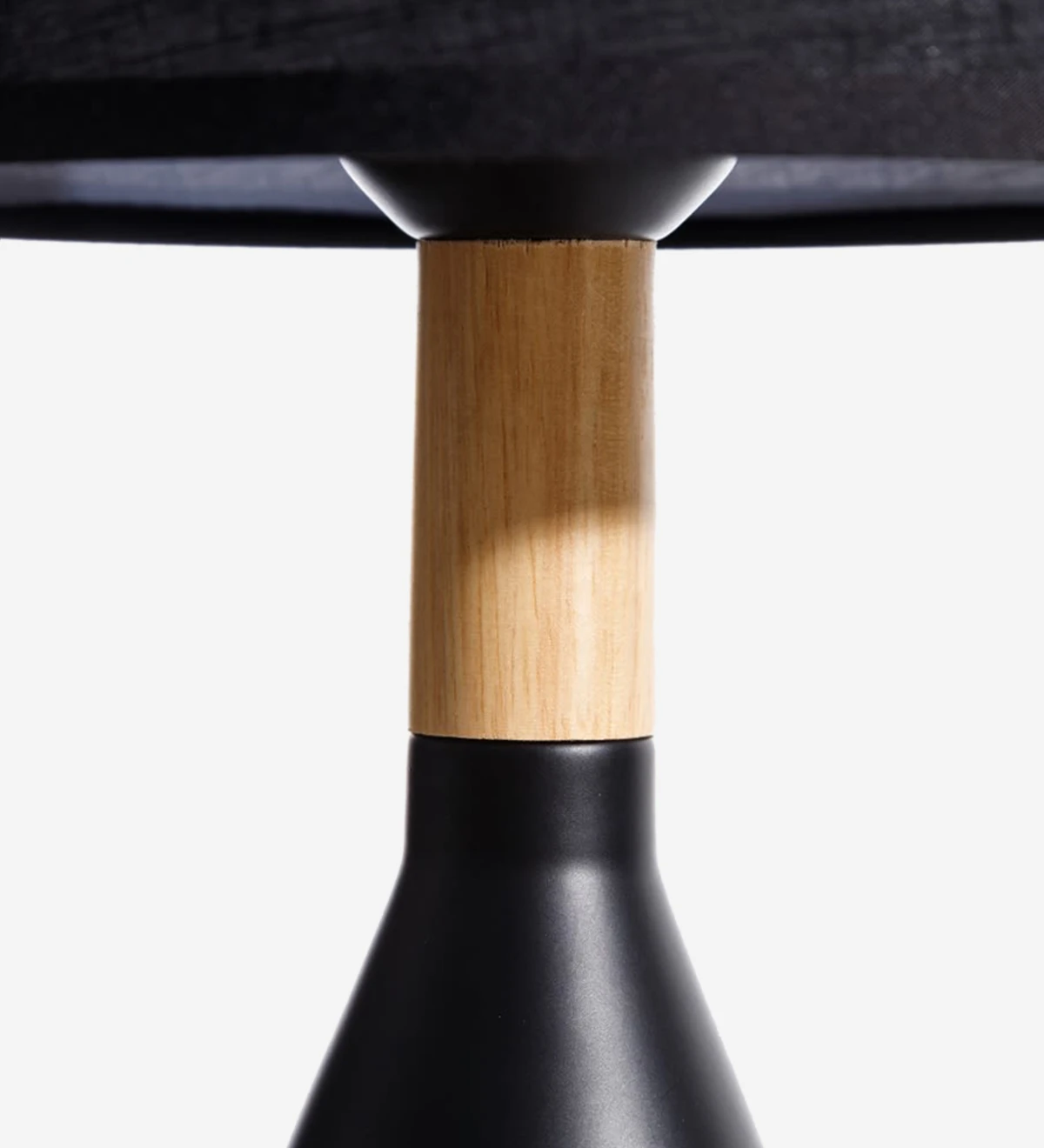 Candeeiro de mesa com base em metal pintado a preto e madeira com abat-jour em tecido preto.