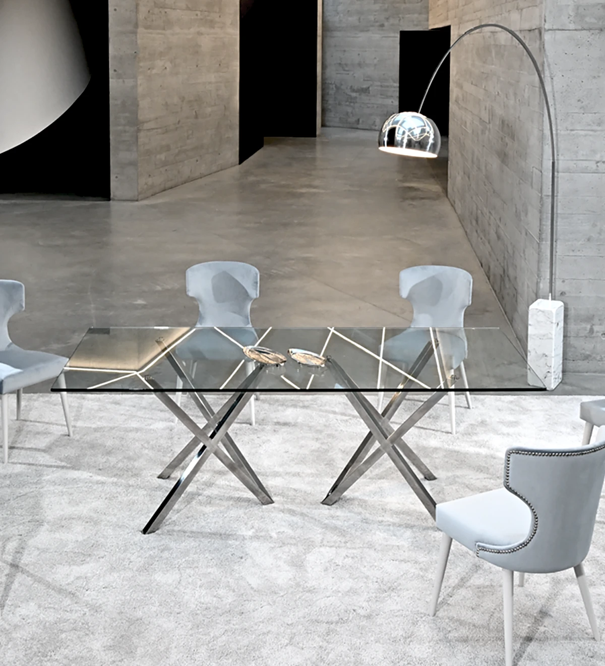 Rectangular dining table with glass top and stainless steel legs.