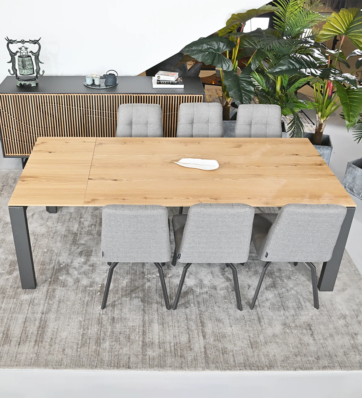 Rectangular extendable dining table with natural oak top, black lacquered metal legs.