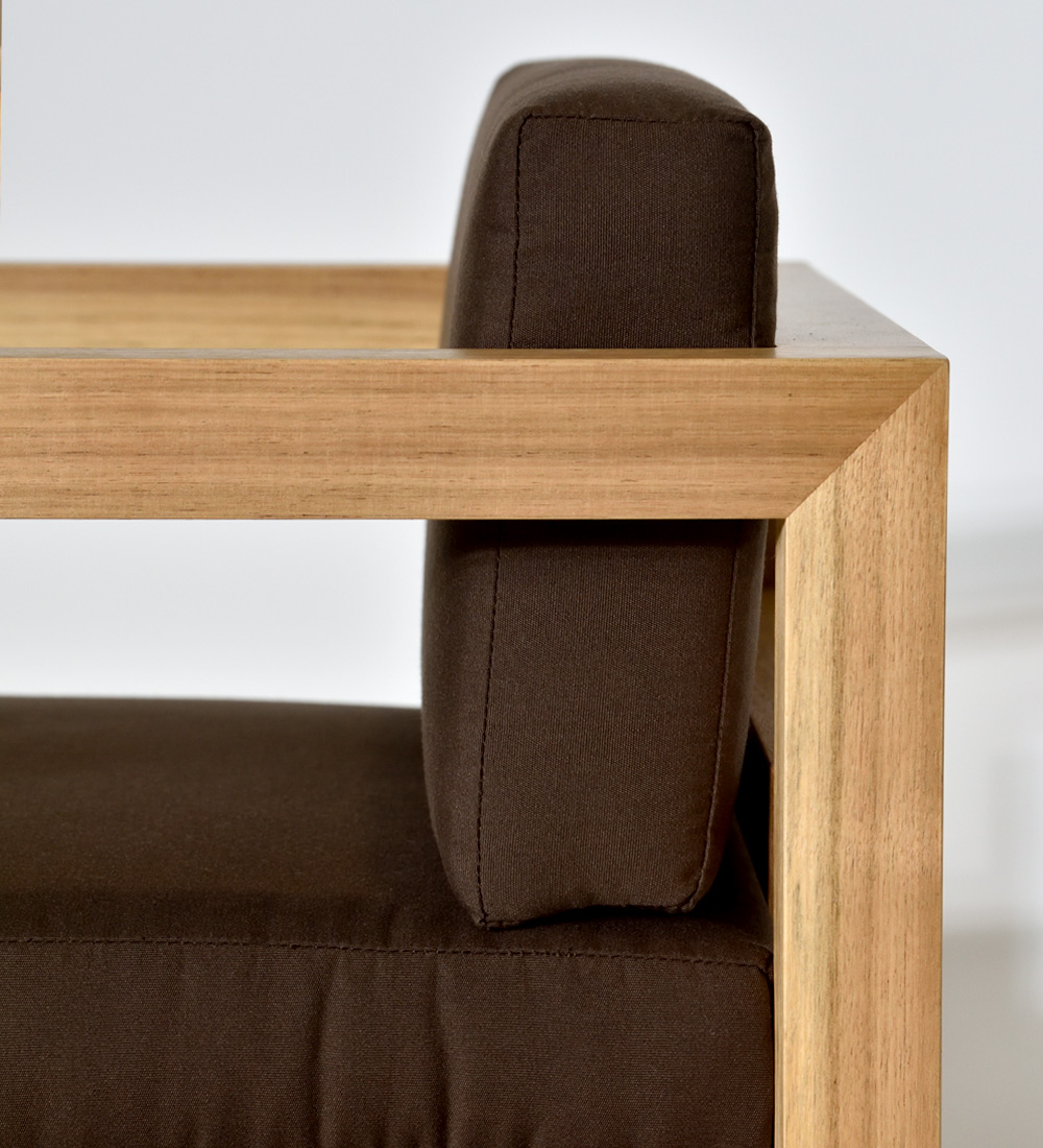 Chair with arms, fabric upholstered cushions, and natural wood structure.