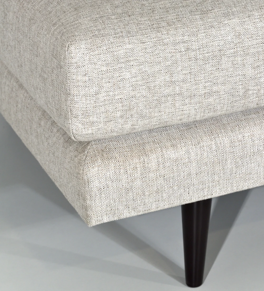 Puff upholstered in fabric, with dark brown lacquered feet.
