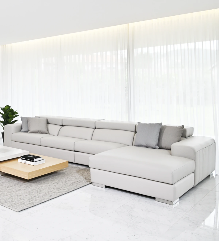 Sofá de 3 plazas con chaise longue, tapizado en ecopiel gris claro, con reposacabezas reclinables.
