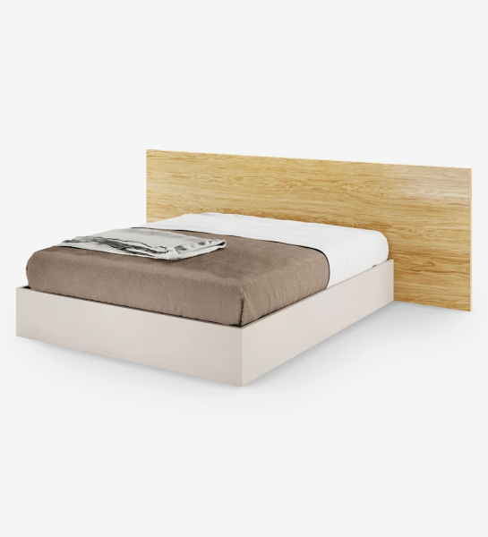 Lit double avec tête de lit en chêne naturel et sommier perlé, avec rangement via un lit surélevé.