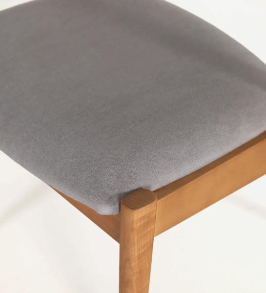 Cadeira em madeira de freixo cor mel, com assento e costa estofados a tecido.