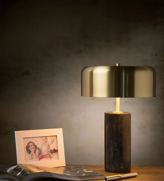 Lámpara de mesa con base de mármol negro y pantalla de latón dorado mate.