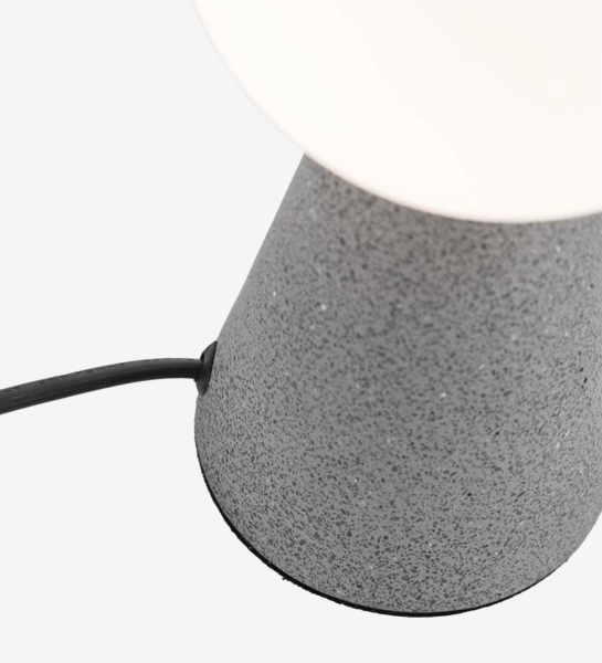 Table lamp with gray concrete base and opal glass diffuser.
