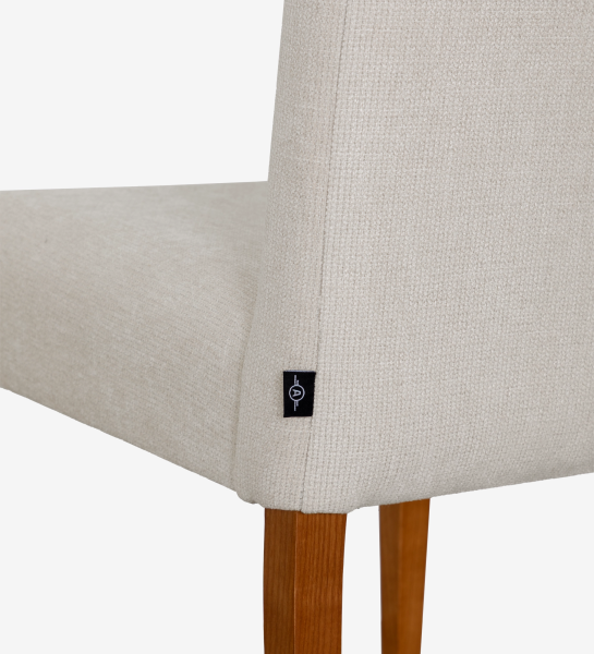 Chair upholstered in beige fabric, with honey-colored wooden legs.