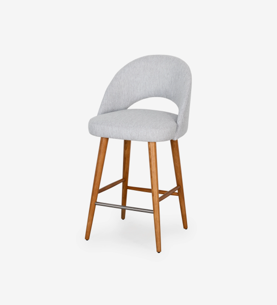 Stool with light grey fabric upholstered, with honey-colored wooden feet.