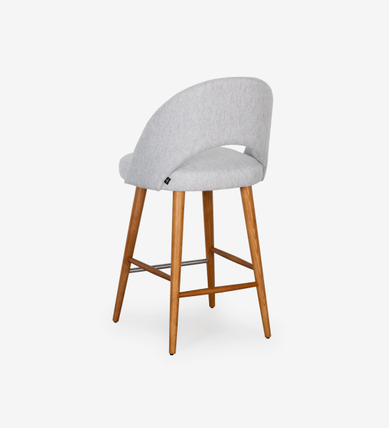 Stool with light grey fabric upholstered, with honey-colored wooden feet.